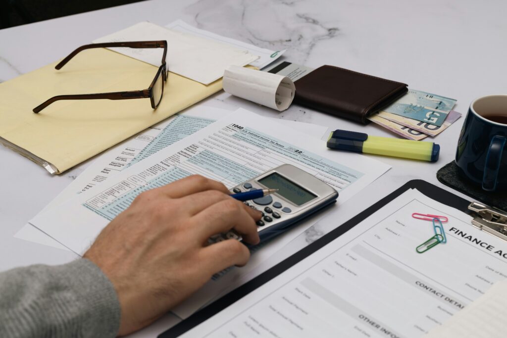 Interior, a desk littered with tax forms and a calculator, for “How Are Alternative Assets Taxed in the US, and What Should Investors Know?”