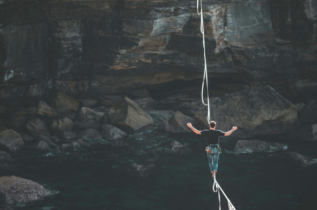 A man walking across a tight rope over a cliff face, for "Quiz: What’s Your Risk Tolerance for Market Crashes?"