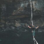 A man walking across a tight rope over a cliff face, for "Quiz: What’s Your Risk Tolerance for Market Crashes?"